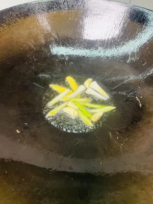 Tumis bahan-bahan: Dengan menggunakan minyak sisa menggoreng perut babi di wajan, tumis siung bawang putih, irisan jahe, dan akar tunas bawang putih hingga harum, lalu tambahkan paprika hijau dan merah dan tumis selama 1 menit.