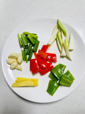 Bahan-bahan: Hancurkan siung bawang putih, iris jahe, cuci tunas bawang putih dan pisahkan bagian putih, akar, dan hijau bawang putih menjadi potongan kecil, serta potong paprika hijau dan merah menjadi potongan kecil.