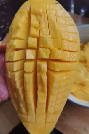 Die Mango halbieren und versuchen, das Fruchtfleisch auf jede erdenkliche Weise herauszulösen.