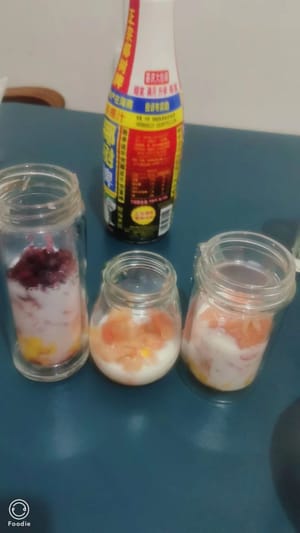 Los geht's mit dem Zusammensetzen! Zuerst eine Schicht Mangostücke auf den Boden geben, dann eine Schicht Grapefruit hinzufügen und die untere Hälfte der Flasche mit Milch füllen, um das Fruchtfleisch zu halten.