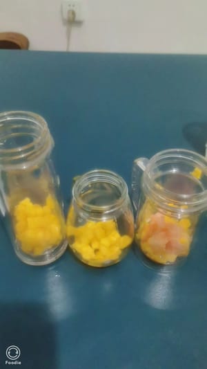 Los geht's mit dem Zusammensetzen! Zuerst eine Schicht Mangostücke auf den Boden geben, dann eine Schicht Grapefruit hinzufügen und die untere Hälfte der Flasche mit Milch füllen, um das Fruchtfleisch zu halten.