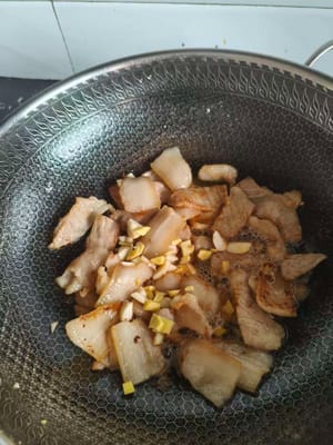 Stir-fry the pork belly until fat is released. Add ginger, garlic, and cooking wine. Stir-fry until fragrant.