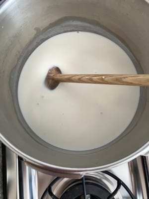 将牛奶混合物逐渐加入沸腾的糖水中，并不断搅拌，以防止变黄并粘在锅上