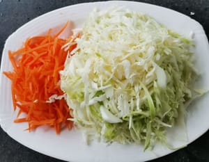 Wash the cabbage thoroughly then cut it into thin, long pieces. Wash the carrots thoroughly then peel them and cut them into thin, long pieces.