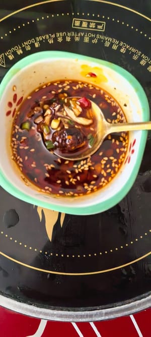 tritare l'aglio, tagliare il cipollotto a pezzetti, tritare il peperone verde, aggiungere 3 grammi di sale, 5 ml di aceto balsamico, 8 ml di salsa di ostriche, 10 ml di salsa bianca bollente, 10 ml di olio rosso piccante, mescolare bene, condire con olio caldo per esaltare il sapore