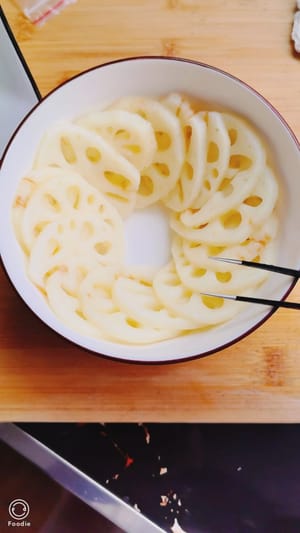 Placez les tranches de racine de lotus refroidies dans un bol et ajoutez 40 grammes de cacahuètes frites au milieu