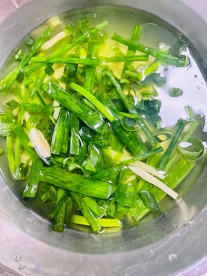 Den geriebenen Ingwer und die Frühlingszwiebeln in eine Schüssel geben, 150 ml Wasser hinzufügen, Ingwer und Frühlingszwiebeln mehrmals mit den Händen verreiben und den Ingwer- und Frühlingszwiebelsaft auspressen.