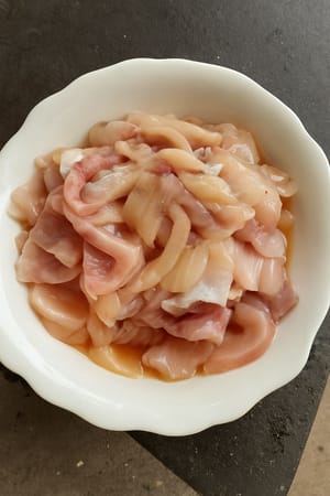 Comience a marinar agregando sal, aceite, vino kaoliang y salsa de soja a los filetes de pescado.