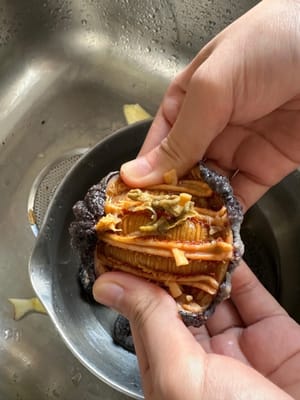 해삼이 부드러워질 때까지 물에 불린 후, 배를 가르는 부분을 따라 반으로 갈라줍니다. 앞쪽의 모래주머니, 내장(하얀 단단한 심), 그리고 안쪽 벽의 하얀 힘줄 주변의 모래를 제거합니다. 깨끗한 물로 충분히 헹궈줍니다.

모래주머니는 반드시 완전히 제거해야 합니다. 그렇지 않으면 먹을 때 거친 식감이 느껴질 수 있습니다. 안쪽 벽의 힘줄은 영양이 풍부한 부분이므로 제거할 필요가 없습니다.