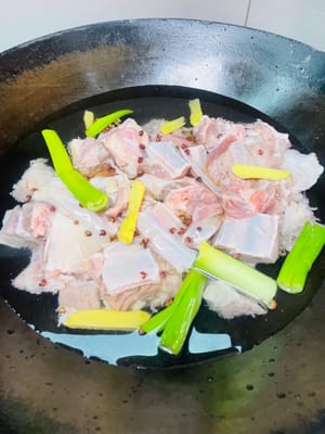 Poner las chuletas de cordero limpias en una olla con agua fría, añadir vino blanco, pimienta en grano, gajos de cebolleta y rodajas de jengibre. Después de que hierva el agua, cocinar durante 5 minutos, sacarlas, enjuagarlas con agua tibia y escurrirlas (si no están escurridas, saltearlas primero en la olla para secarlas).
