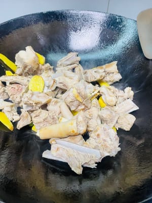 Calentar el aceite en un wok, añadir las rodajas de jengibre y las partes blancas del ajo y sofreír a fuego medio-bajo hasta que desprendan su aroma. A continuación, añadir las chuletas de cordero preparadas y sofreírlas a fuego alto hasta que la superficie esté ligeramente dorada, realzando así su aroma.