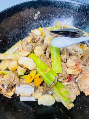 Rocíe una cucharada de vino blanco por el borde del wok para que libere el aroma, luego vierta la salsa preparada y saltee un rato para que las chuletas de cordero se impregnen de ella. A continuación, añada la raíz de angélica, la cáscara de mandarina seca, el espino blanco y la angélica sinensis, junto con las castañas de agua y la caña de azúcar. Añada una cucharada de sal como sal base y remueva todo bien.