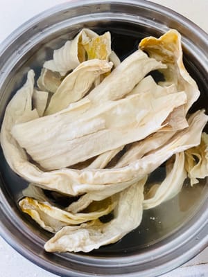 Remoje los palitos de tofu seco en agua fría durante 20-30 minutos con antelación, hasta que estén completamente blandos y sin núcleo duro. Después del remojo, córtelos en trozos y reserve.