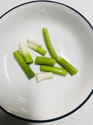 Lavar los brotes de ajo, separar las partes blancas y verdes de los ajos y cortarlos en trozos, luego reservar.