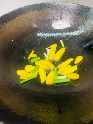 Calentar el aceite en un wok, añadir las rodajas de jengibre y las partes blancas del ajo y sofreír a fuego medio-bajo hasta que desprendan su aroma. A continuación, añadir las chuletas de cordero preparadas y sofreírlas a fuego alto hasta que la superficie esté ligeramente dorada, realzando así su aroma.