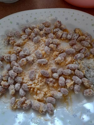 Prendete 1/3 delle arachidi, aggiungete 2 cucchiai di soluzione di zucchero, mescolate bene e cospargete con 3 cucchiai di miscela di farina, agitate finché le arachidi non saranno ricoperte.