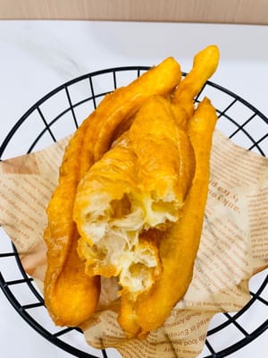 Turn the heat to medium. Pinch the dough sticks together (don't twist them, or they won't expand). Place them in the pan. Once in the pan, they will expand. Fry them frequently to evenly cook. Fry until golden and crispy. Remove from heat and drain.
