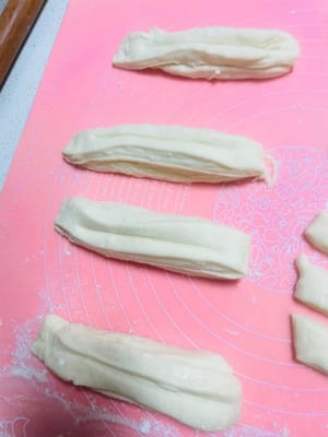 Then cut the long strips into small strips about 2 cm wide, use a spray bottle to spray some water on the small strips, stack two strips together, press hard in the middle with chopsticks to make a mark, and the raw dough of the fried dough sticks is ready.