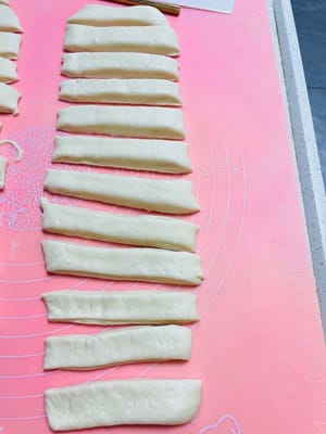 Then cut the long strips into small strips about 2 cm wide, use a spray bottle to spray some water on the small strips, stack two strips together, press hard in the middle with chopsticks to make a mark, and the raw dough of the fried dough sticks is ready.