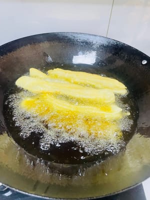 Turn the heat to medium. Pinch the dough sticks together (don't twist them, or they won't expand). Place them in the pan. Once in the pan, they will expand. Fry them frequently to evenly cook. Fry until golden and crispy. Remove from heat and drain.