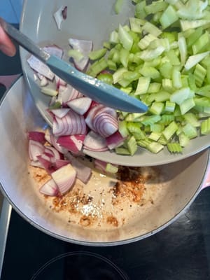 Dans la même poêle, ajouter l'oignon, le céleri et les carottes. Faire revenir jusqu'à ce qu'ils soient légèrement tendres.