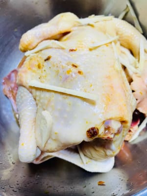 鶏肉を洗い、水を切ります。塩焼きチキンパウダーを鶏肉の内側と外側に均等に塗ります。鶏肉に千切り生姜を詰め、全体に振りかけ、味をなじませるようにマッサージします。クチナシ水と残った調味料（もしあれば）を加えてよく混ぜ、冷蔵庫で一晩マリネします（時々かき混ぜます）。