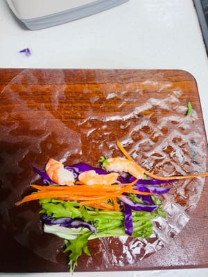 채 썬 보라색 양배추, 엔다이브, 채 썬 당근, 새우를 순서대로 준비합니다. 가장자리 쪽부터 말기 시작합니다. 약 3분의 1 정도 말았을 때, 스프링롤 wrappers의 양쪽 끝을 안쪽으로 접어 가장자리를 봉한 다음, 원하는 모양이 될 때까지 빠르게 말아줍니다. 스프링롤 wrappers가 작업대에 달라붙어 모양이 흐트러지지 않도록 모든 과정을 신속하고 효율적으로 진행해야 합니다.