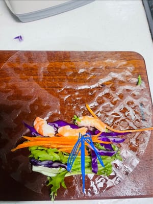 채 썬 보라색 양배추, 엔다이브, 채 썬 당근, 새우를 순서대로 준비합니다. 가장자리 쪽부터 말기 시작합니다. 약 3분의 1 정도 말았을 때, 스프링롤 wrappers의 양쪽 끝을 안쪽으로 접어 가장자리를 봉한 다음, 원하는 모양이 될 때까지 빠르게 말아줍니다. 스프링롤 wrappers가 작업대에 달라붙어 모양이 흐트러지지 않도록 모든 과정을 신속하고 효율적으로 진행해야 합니다.