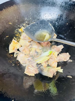 Push the chicken to the side of the wok and add the ginger, garlic, and scallions. Stir-fry until fragrant.
Pour 1 tablespoon of cooking wine from the side of the wok. Add 2 tablespoons of light soy sauce, 1 tablespoon of oyster sauce, 1 tablespoon of dark soy sauce, and the rock sugar. Stir-fry until evenly combined.