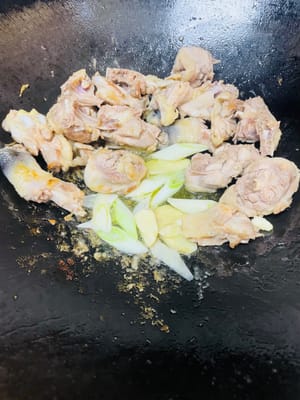 Push the chicken to the side of the wok and add the ginger, garlic, and scallions. Stir-fry until fragrant.
Pour 1 tablespoon of cooking wine from the side of the wok. Add 2 tablespoons of light soy sauce, 1 tablespoon of oyster sauce, 1 tablespoon of dark soy sauce, and the rock sugar. Stir-fry until evenly combined.