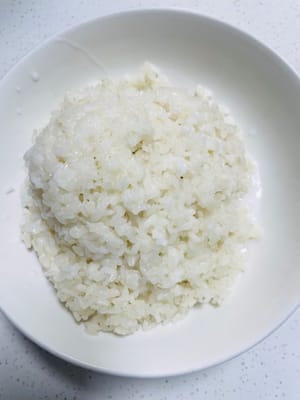 Une fois le riz gluant cuit à la vapeur, versez-le dans un récipient et versez-y les deux tiers du lait de coco. Remuez bien pour que le riz absorbe le lait de coco. Laissez reposer 10 à 20 minutes.