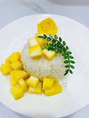 Montage
Coupez le reste de mangue en petits morceaux. Placez le riz gluant imbibé de lait de coco dans un saladier, puis retournez-le sur l'assiette contenant les fleurs de manguier. Ajoutez les dés de mangue et versez le tiers restant du lait de coco par-dessus. Ce riz gluant à la mangue et au lait de coco est prêt à être dégusté.