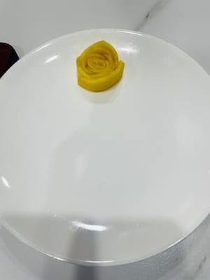 Pour les fleurs de mangue :
Pendant que le riz gluant absorbe le lait de coco, préparez les mangues. Pelez la mangue et coupez-la en fines tranches pour former les fleurs de mangue. Enroulez d’abord la plus petite tranche de mangue pour former le centre de la fleur. Ensuite, enroulez les tranches de mangue restantes autour du centre pour former une petite fleur. Cela donnera un résultat plus joli.