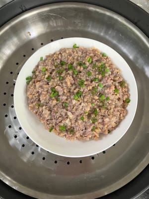 Placez le porc sur de l'eau bouillante, faites-le cuire à la vapeur pendant 10 minutes et garnissez d'oignon vert haché.