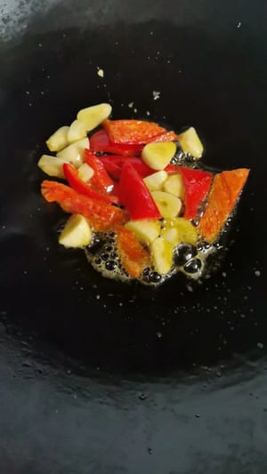 中華鍋に油を熱し、スライスしたニンニクと赤唐辛子を加えて香りが出るまで炒め、刻んだソーセージを加えます。