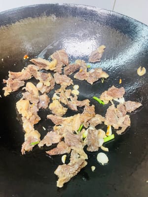 Salteado final:
Añadir un poco más de aceite al wok y sofreír las cebolletas picadas hasta que desprendan un aroma fragante. Añadir las rodajas de falda de res y sofreír durante 1 minuto. Añadir 200 ml del caldo de la falda de res y reducir a fuego medio-alto hasta que la salsa espese.