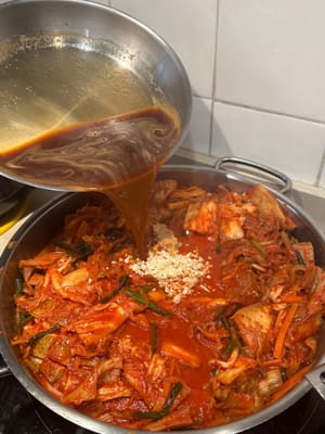Anschließend in den Topf geben, sodass das gesamte Kimchi mit Brühe bedeckt ist.