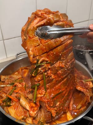 Anschließend den Schweinebauch wenden, sodass die Schwarte nach unten zeigt, und auch das Kimchi wenden, damit es nicht anklebt.