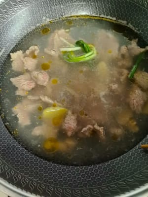 Ponga unas rodajas de jengibre y una sección de cebolla verde en una olla con agua, vierta la carne marinada en la olla, encienda el fuego y cocine por un minuto.
