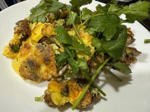 La frittella di ostriche fritte viene servita e decorata con coriandolo. È pronto da mangiare.