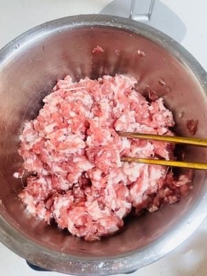 Aggiungere sale, brodo di pollo, pepe e zucchero al macinato di maiale. Quindi, aggiungere l'acqua di cipollotto e zenzero in tre riprese. Mescolare in una direzione ogni volta fino a quando il macinato di maiale non avrà completamente assorbito l'acqua e diventerà appiccicoso ed elastico.