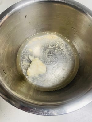 In una ciotola, mescolate 3 g di sale, 5 g di zucchero, 20 g di strutto e circa 40 g di acqua tiepida, mescolando bene. Una volta che l'acqua si è raffreddata a una temperatura non troppo calda al tatto (circa 30 gradi Celsius), aggiungete 1 g di lievito. Non usate acqua bollente, perché ucciderebbe il lievito e l'impasto non lieviterebbe!