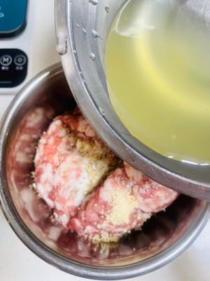 Aggiungere sale, brodo di pollo, pepe e zucchero al macinato di maiale. Quindi, aggiungere l'acqua di cipollotto e zenzero in tre riprese. Mescolare in una direzione ogni volta fino a quando il macinato di maiale non avrà completamente assorbito l'acqua e diventerà appiccicoso ed elastico.