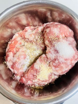 Aggiungere sale, brodo di pollo, pepe e zucchero al macinato di maiale. Quindi, aggiungere l'acqua di cipollotto e zenzero in tre riprese. Mescolare in una direzione ogni volta fino a quando il macinato di maiale non avrà completamente assorbito l'acqua e diventerà appiccicoso ed elastico.