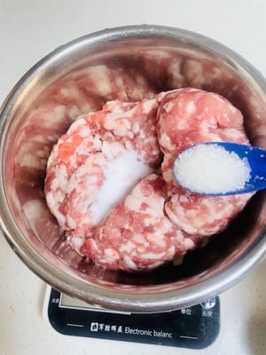 Aggiungere sale, brodo di pollo, pepe e zucchero al macinato di maiale. Quindi, aggiungere l'acqua di cipollotto e zenzero in tre riprese. Mescolare in una direzione ogni volta fino a quando il macinato di maiale non avrà completamente assorbito l'acqua e diventerà appiccicoso ed elastico.
