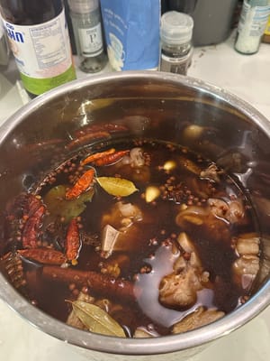 在锅中加入所有如图所示的香料和所有调味品。加入沸水，淹没所有食材。