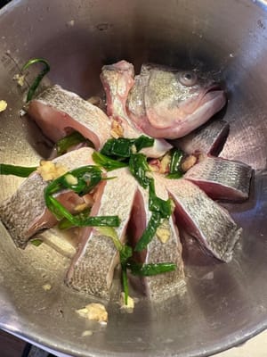 Dejar marinar unos 10 minutos. Después, retirar las cebolletas y el jengibre. Reservar el pescado para más tarde.