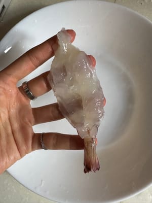 ใช้ด้านหลังของมีดค่อยๆ กดกุ้งเพื่อให้เส้นบางลง