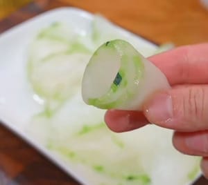 Envuelva las rodajas finas de melón de invierno enjuagadas con agua fría en forma de cono con las manos.