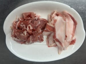 Das Schweinefleisch in dünne Scheiben schneiden und die fetten und mageren Teile trennen.